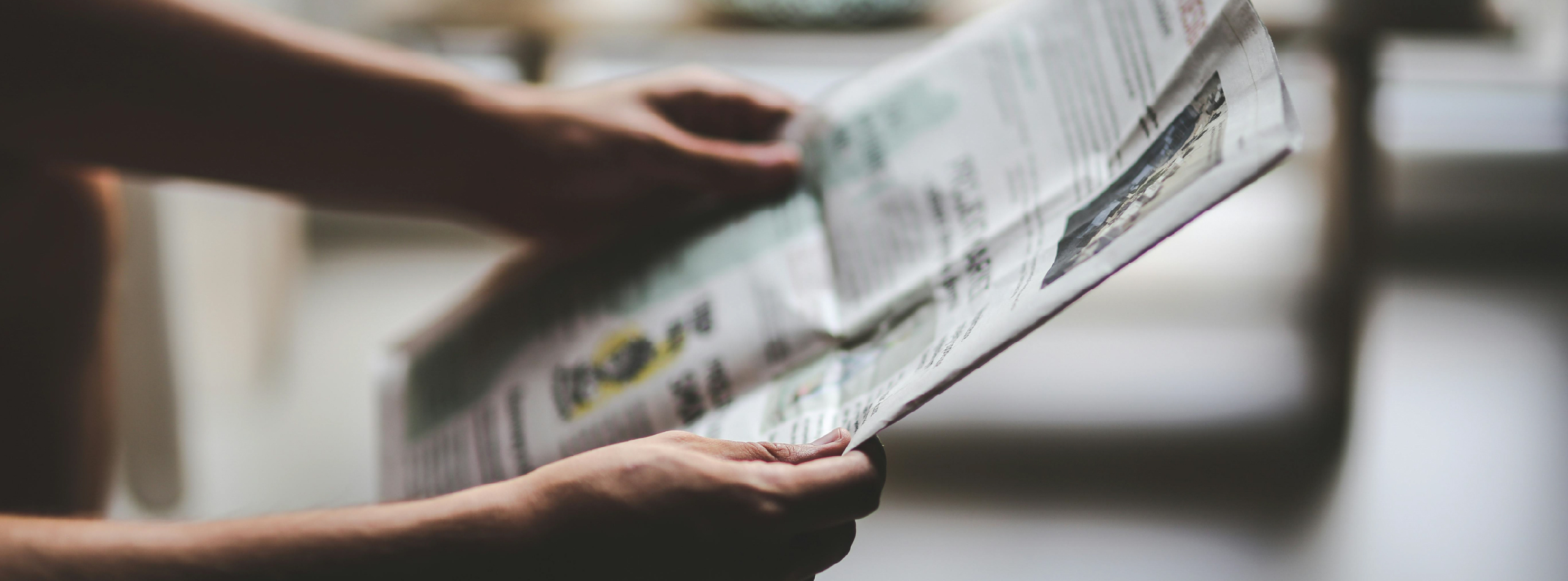 A person sitting in a room, focused on reading a newspaper