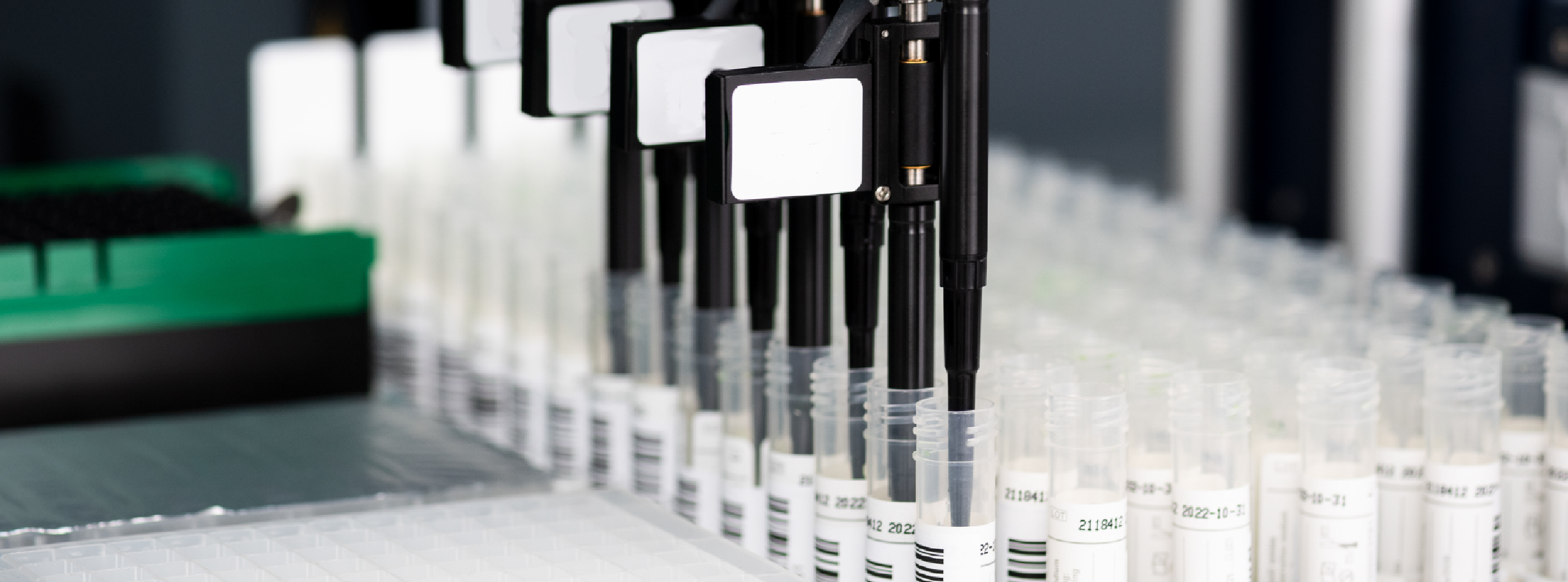 A machine with a row of tubes containing various types of needles arranged neatly on a laboratory countertop.