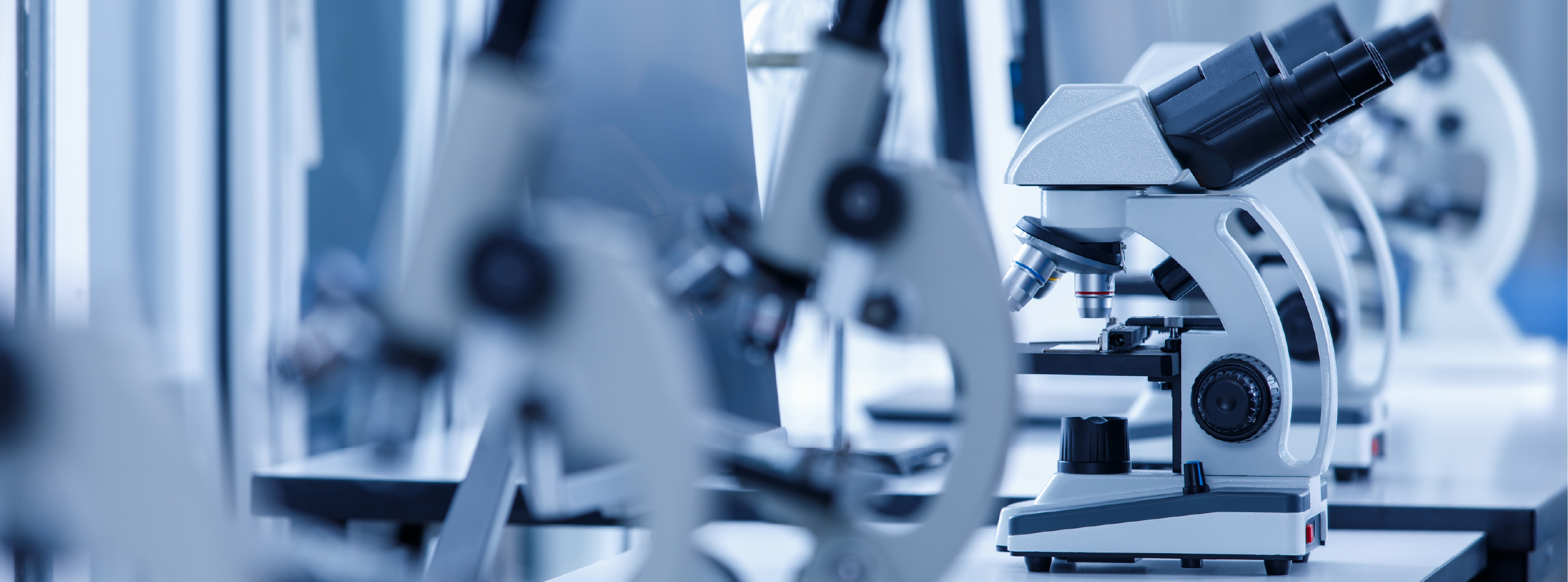 A microscope is prominently displayed on a lab countertop, surrounded by various scientific equipment.