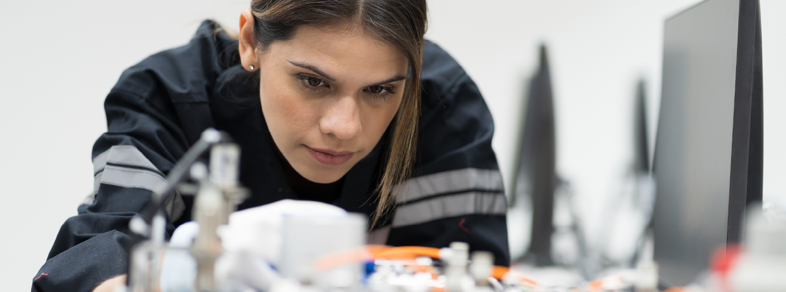A woman focused on her equipment in a laboratory setting, surrounded by scientific equipment and research materials.