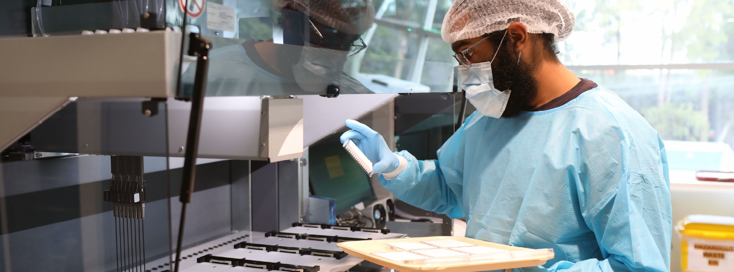 A man in a blue uniform operates a machine, focused on his task in a laboratory setting