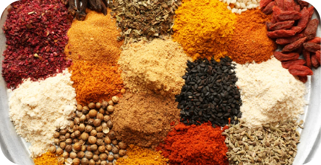 a number of powdered and whole spices arranged in a bowl