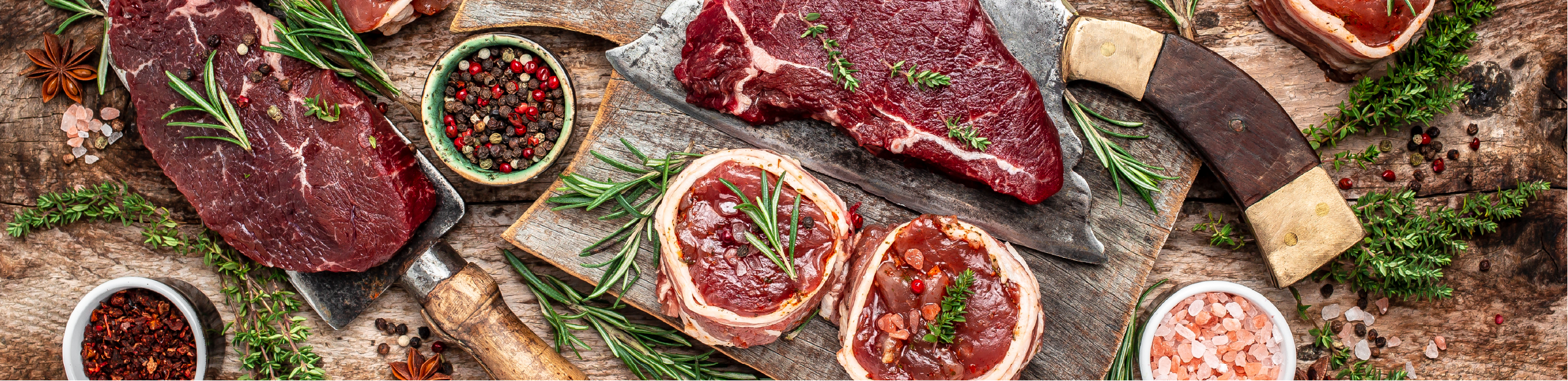 a series of steaks and other beef products sitting on a wooden board with an assortment of salts and peppercorns