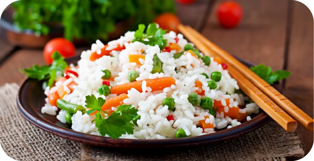 a bowl of rice and vegetables with chopsticks sitting on a wooden table