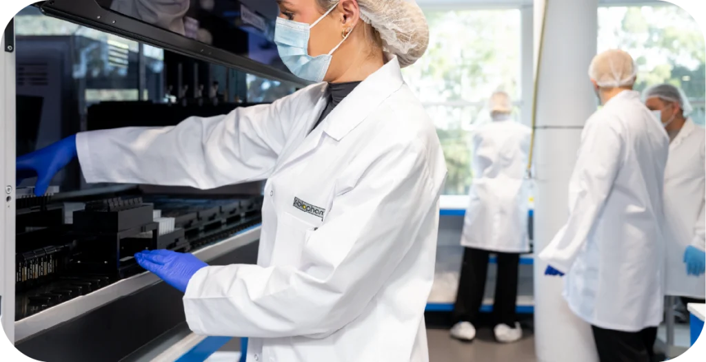 a woman in a lab coat, hairnet and gloves conducting a test for meningitis or similar illnesses