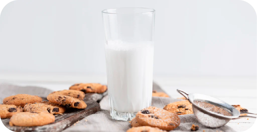 a glass of milk surrounded by chocolate chip cookies. Milk species identification is a critical component of ensuring product quality