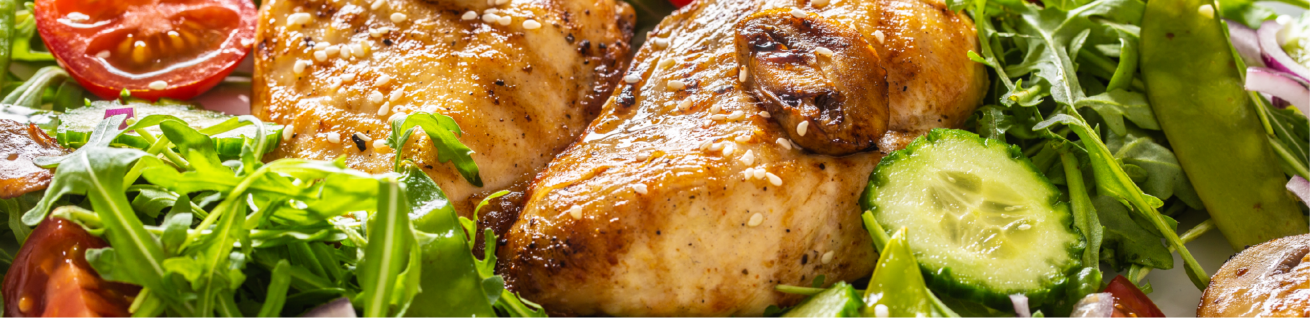 grilled chicken in sauce sits atop a fresh garden salad