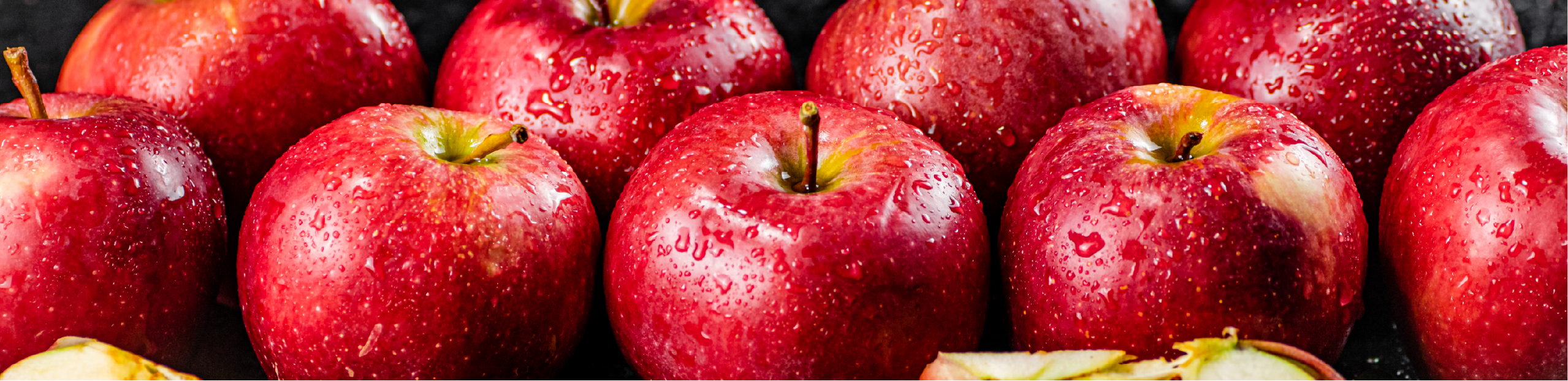 a series of ripe, red apples covered in water droplets