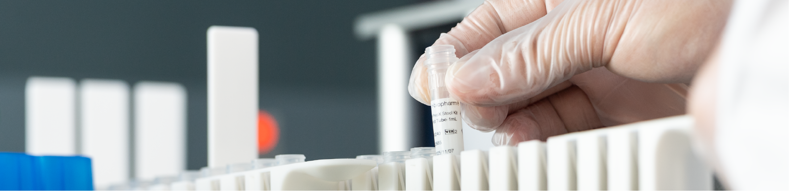 a man in a lab coat places a small tube into a container to prepare for conducing a stool test