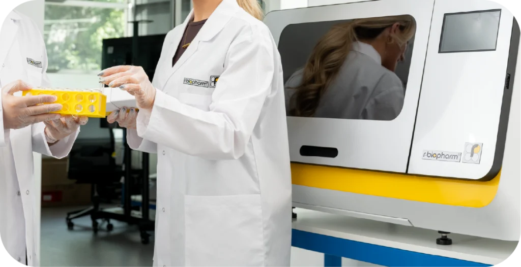 two scientists holding medical diagnostics next to a RIDA®Xtract 24