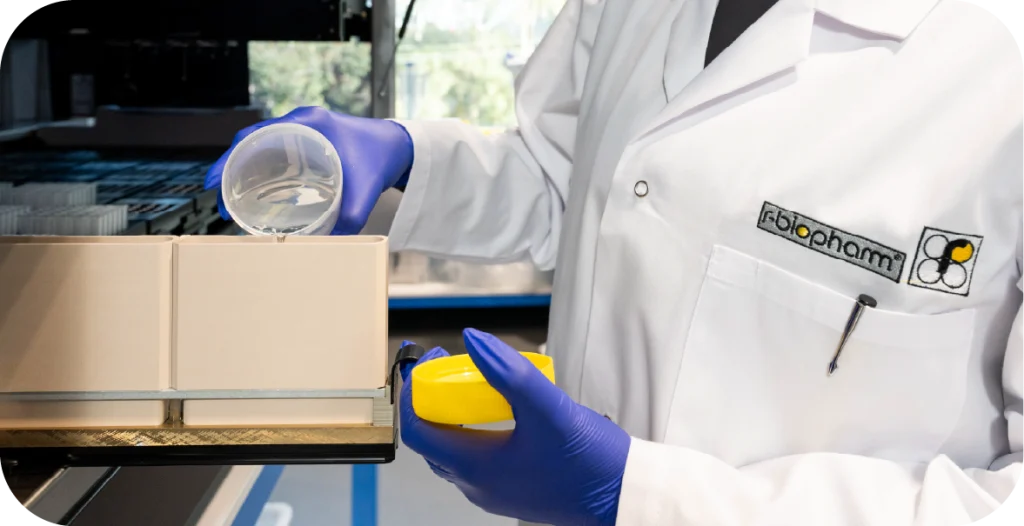 a woman in a lab coat pours liquid into a machine in preparation for performing a RIDA®Xtract 24 Blood DNA Kit test