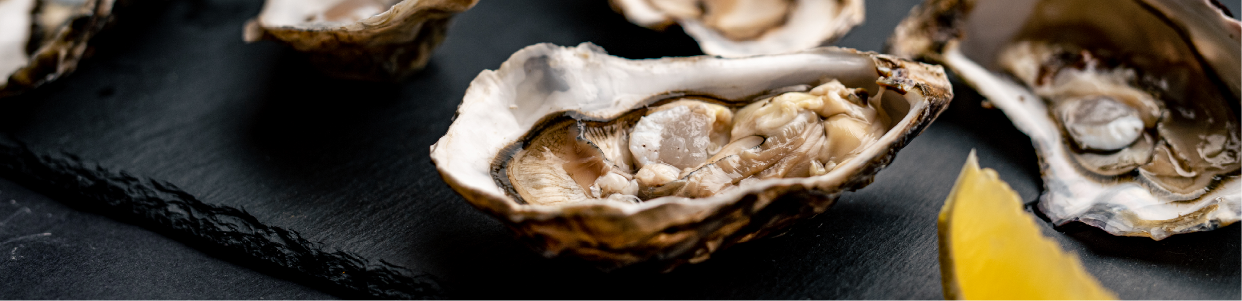 open oysters arranged with lemon wedges on a black table