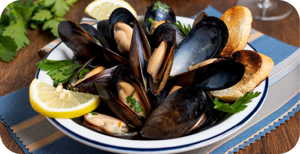 a bowl of mussels with lemon slices in a bowl; a critical marker for shellfish testing