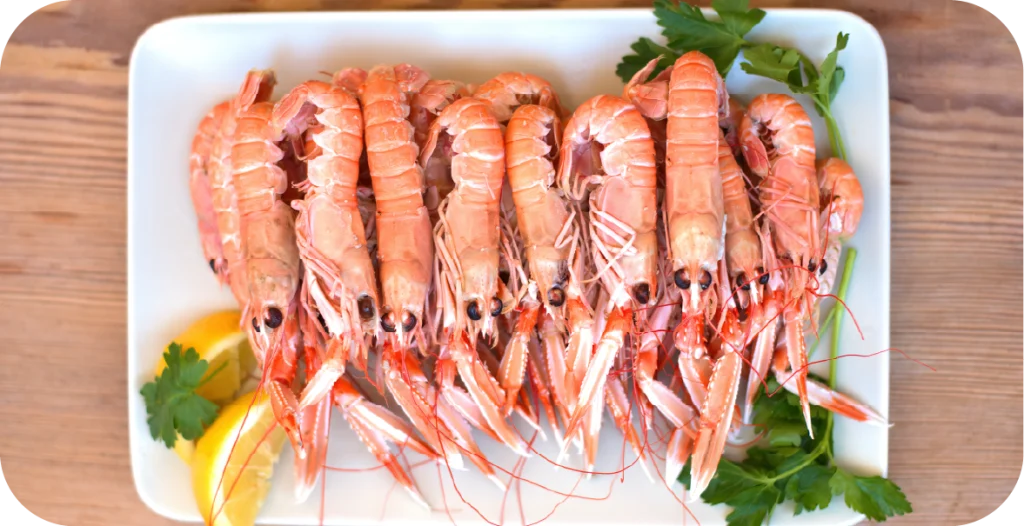 whole prawns arranged on a white plate with parsley and lemon wedges