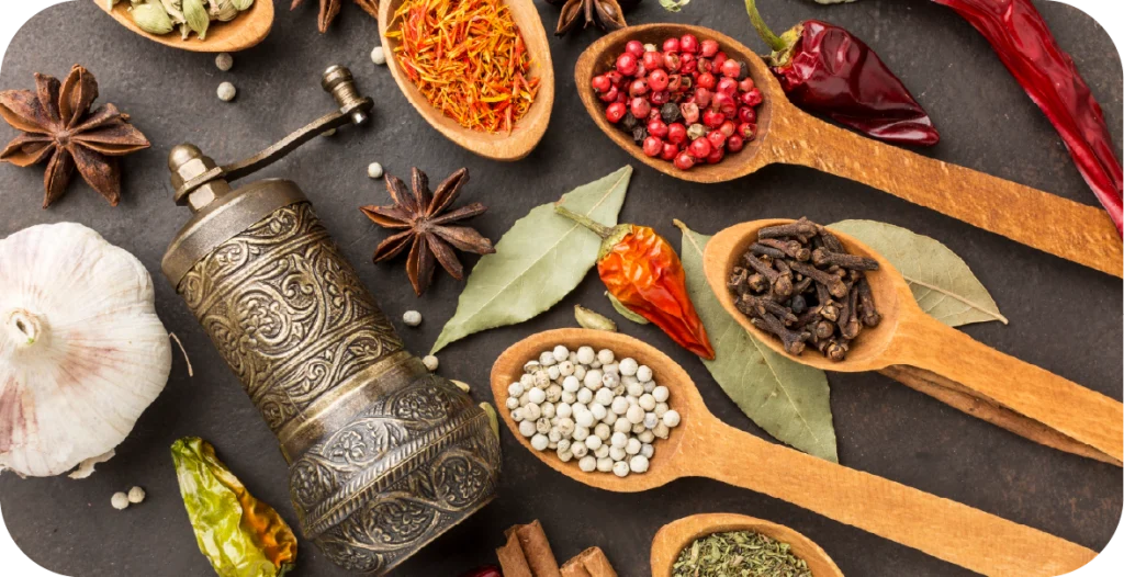 a number of different spices on wooden spoons with a pepper grinder, each requiring spoilage organism testing