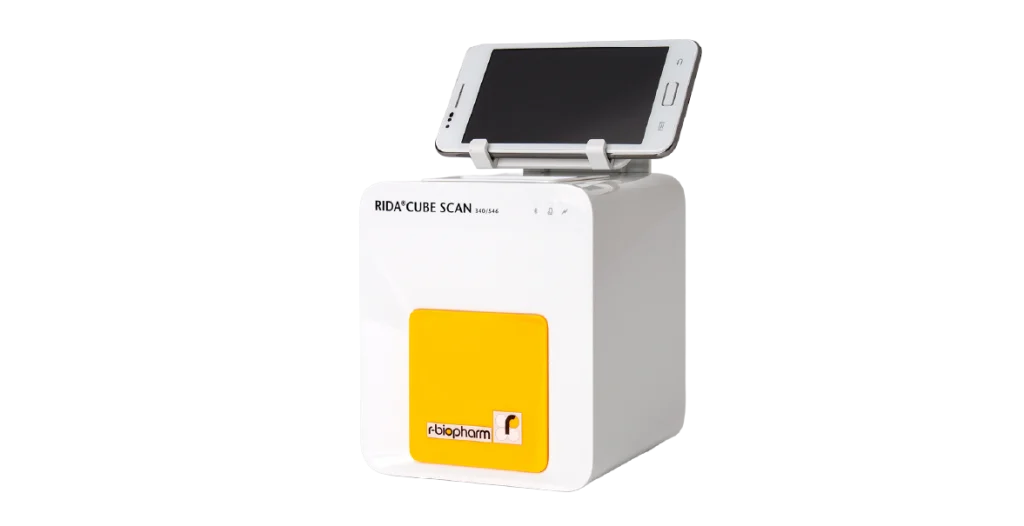 A small white box with a yellow label and mobile phone sitting atop. Used for food and feed analysis