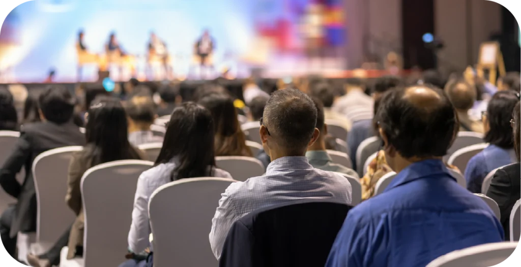 a group of people sitting in an audience for a lecture or seminar being delivered to them