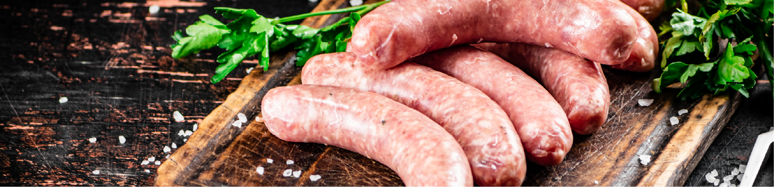 raw sausages on a cutting board surrounded by parsley