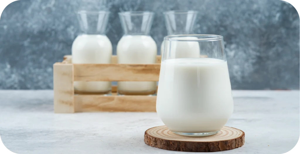 milk in a glass in front of three milk bottles. Milk also needs residue testing