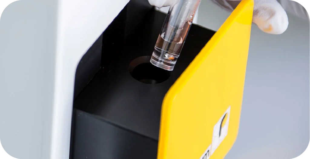 A scientist places a tube into a small white and yellow machine