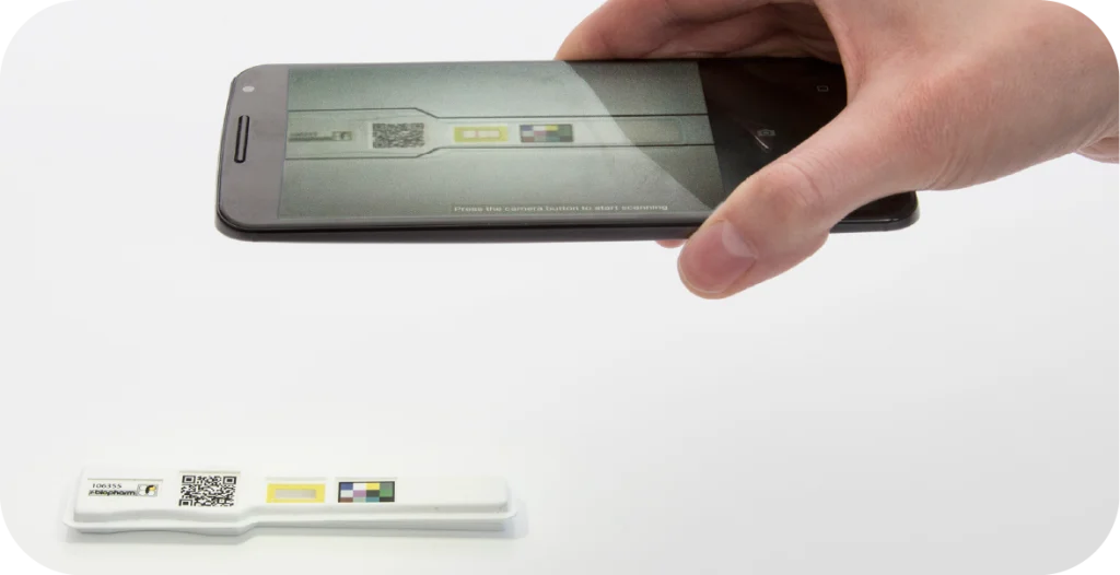 An individual uses a phone to take a photo of a lateral flow test result panel